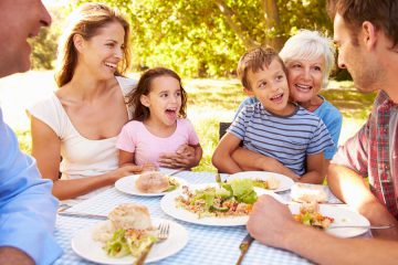 family of grandparents, parents and children eating outside